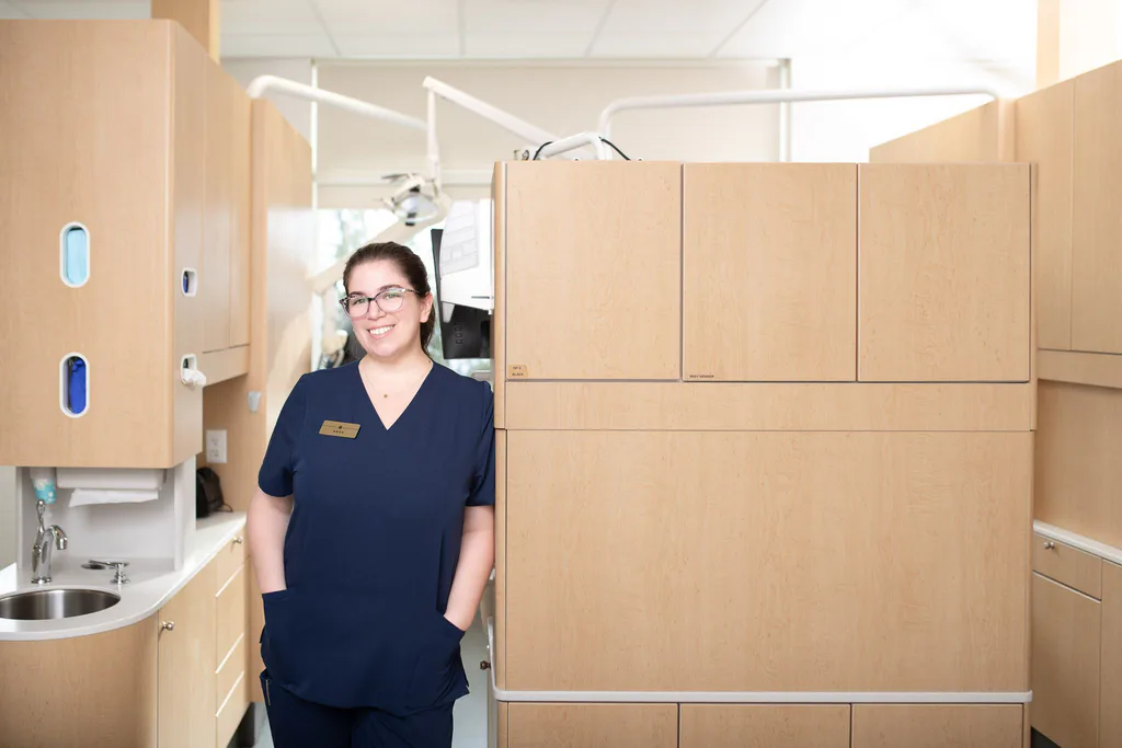 A dental assistant smiling in a bright treatment room