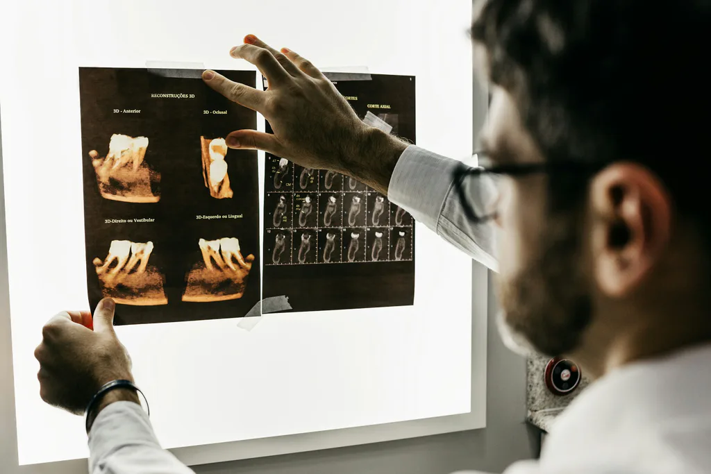 A dentist reviewing a set of dental x-rays on a lit viewing board