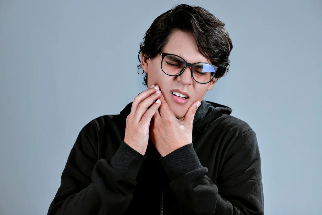 A woman holding her jaw, looking uncomfortable