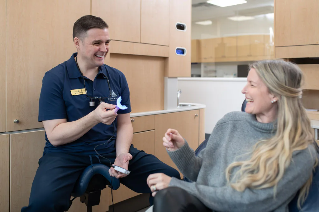 Dr. Michel Séguin laughing with a patient in a bright treatment room at Seven Sails