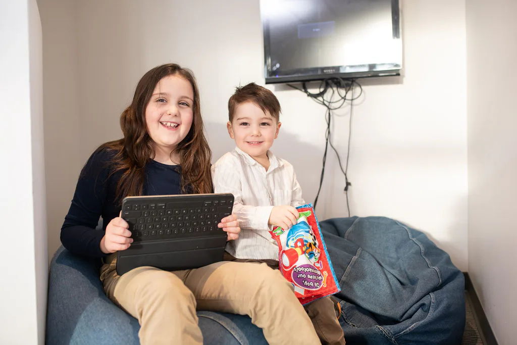 Two children reading together in the waiting room's cosy corner