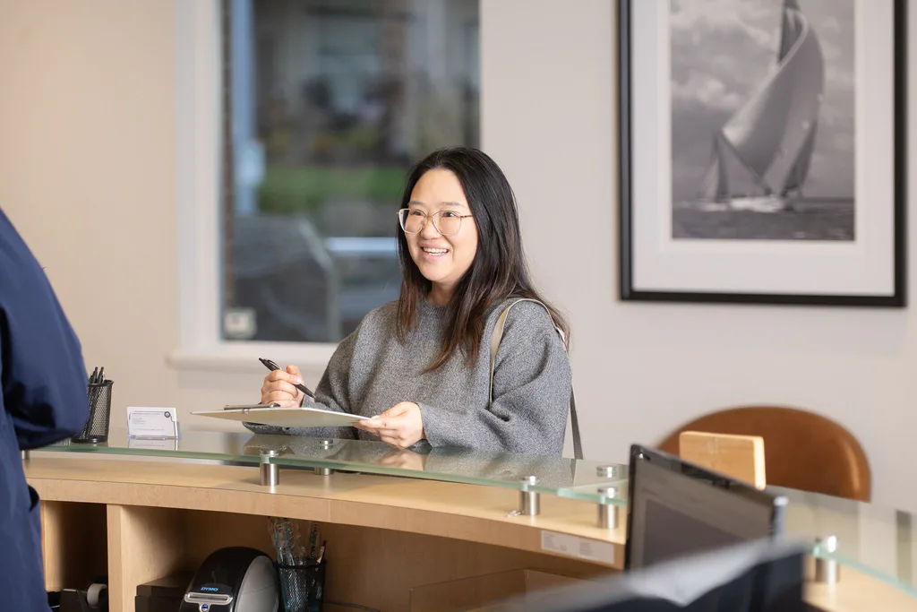 A new patient smiling as she checks in at the curved reception desk