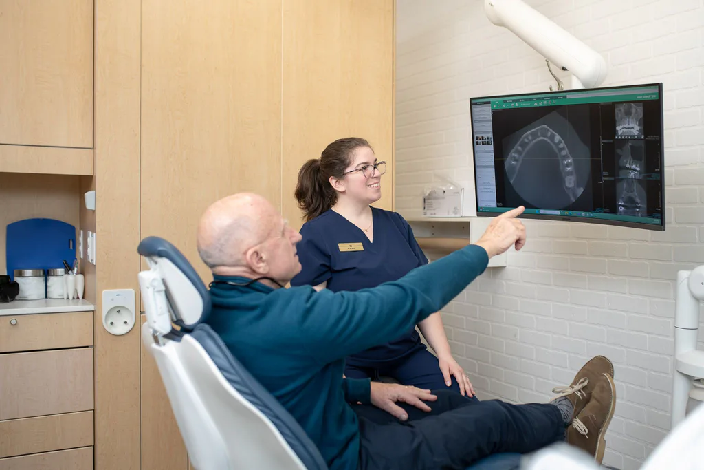 A hygienist walking a patient through his 3D scan on a ceiling-mounted screen