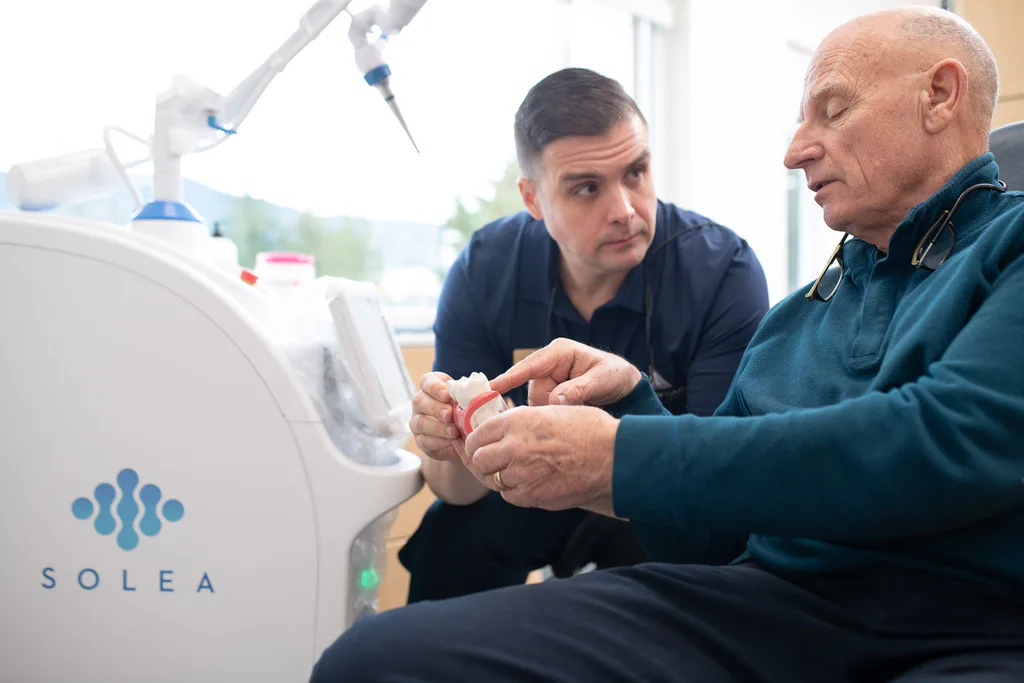 Dr. Séguin calmly explaining a procedure to a patient using a model