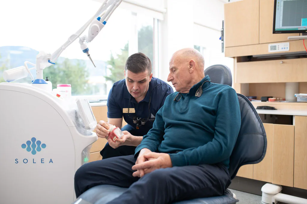 Dr. Séguin talking with a patient beside a window overlooking the mountains
