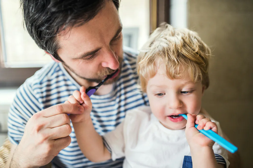 A father and his young son brushing their teeth together