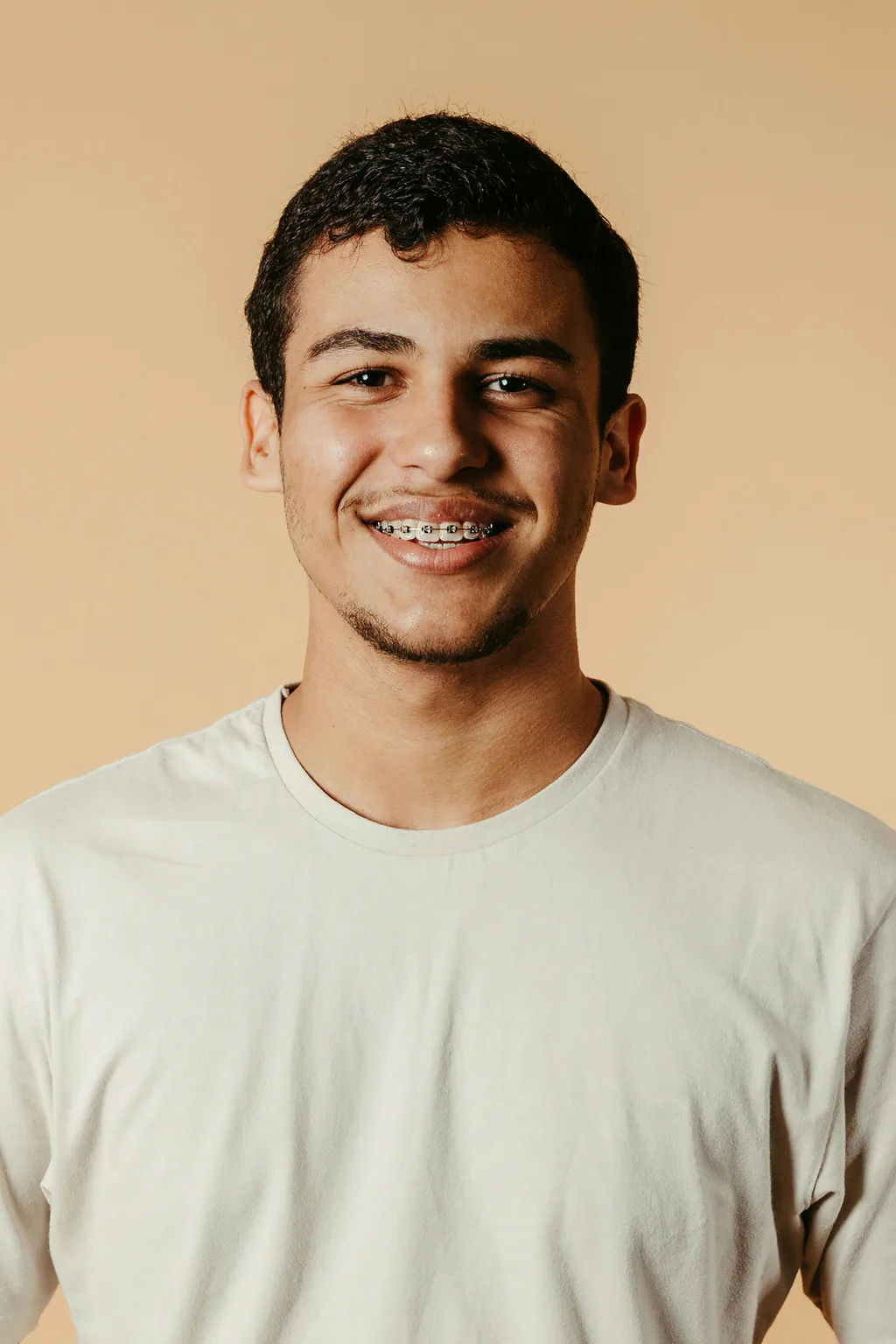 A smiling young man in a cream T-shirt